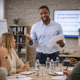 Professioneller Rhetorikkurs im Unternehmen: Ein Trainer vermittelt überzeugende Präsentationstechniken und effektive Argumentationsstrategien vor einem motivierten Team. Das Kommunikationstraining fördert sicheres Auftreten, klare Ausdrucksweise und erfolgreiche Meetings im Business-Kontext.