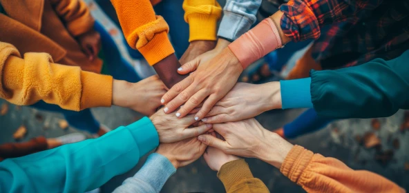 viele Hände sind kreisförmig mittig übereinandergelegt