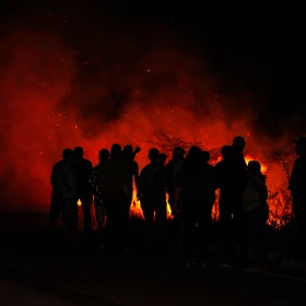 Gruppe Menschen steht vor einem großen Lagerfeuer