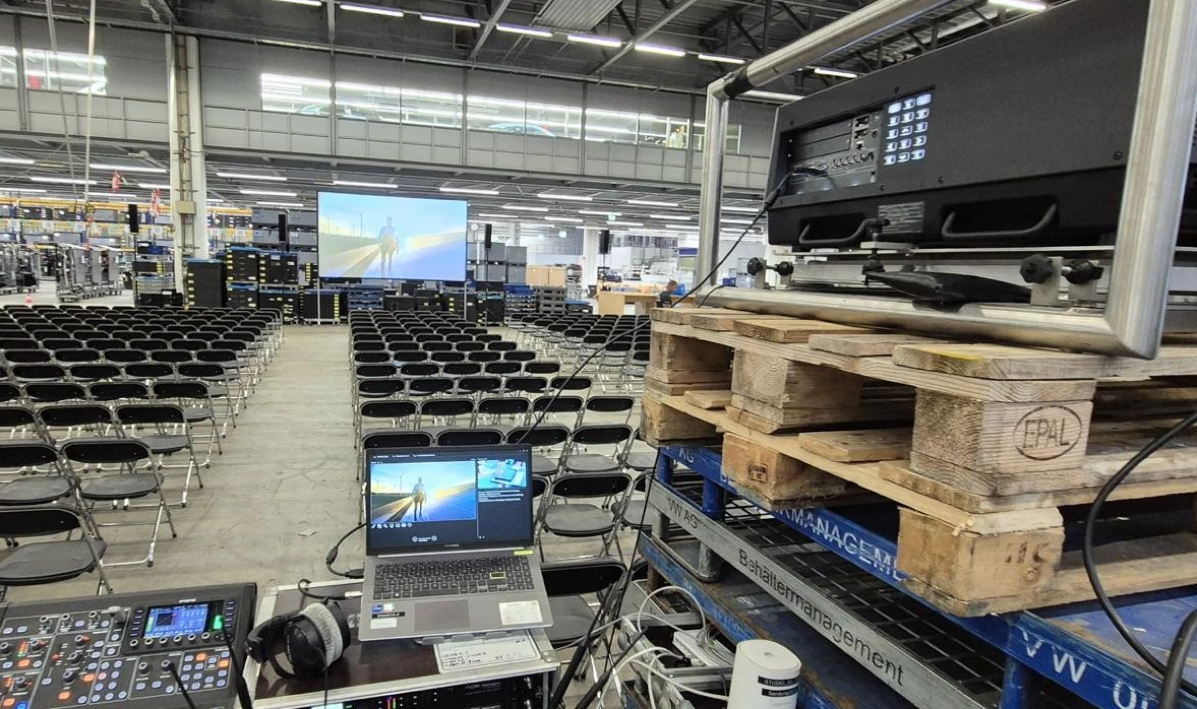 Halle mit mehreren Stühlen und einem Beamer und Leinwand