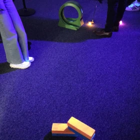 Person schlägt leuchtenten Golfball durch ein Hinderniss